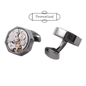 May include: A pair of silver cufflinks with a detailed, exposed clockwork mechanism on one cufflink. The other cufflink is a solid silver design.