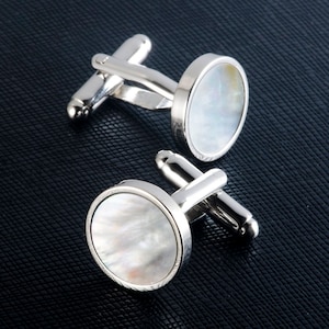 May include: A pair of silver cufflinks with round white mother-of-pearl inserts.