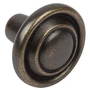 May include: A round, antique brass cabinet knob with a raised centre and a textured finish.
