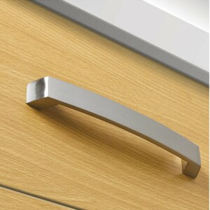 May include: A silver cabinet door handle with a curved design.