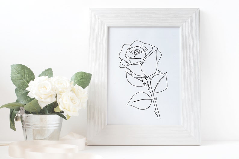 May include: A black and white line drawing of a rose in a white frame. The rose is drawn in a single line, with the stem and leaves also drawn in a single line.