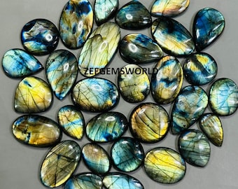 Könnte beinhalten: Eine Sammlung von 25 Labradorit-Edelstein-Cabochons in verschiedenen Blautönen, Grüntönen und Goldtönen. Die Steine sind birnenförmig und haben eine glatte, polierte Oberfläche.