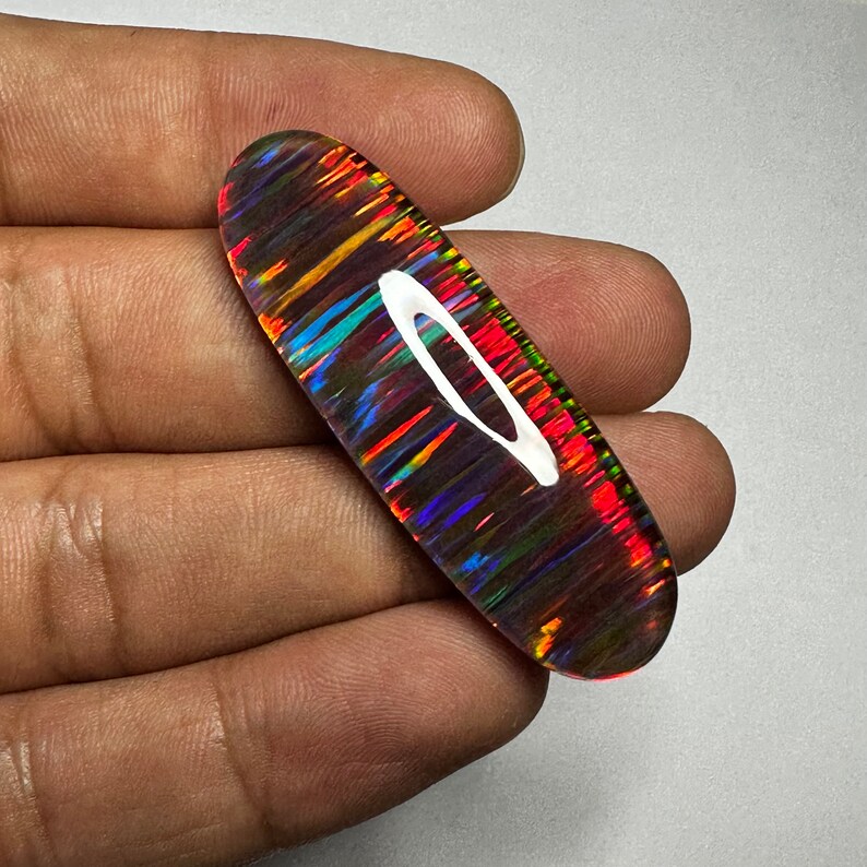 Pu&ograve; includere: Una pietra preziosa di opale ovale di colore vivace con riflessi iridescenti arcobaleno, tra cui rosso, arancione, giallo, verde, blu e viola.