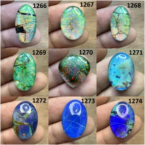 Könnte beinhalten: Neun ovale Edelsteine mit schillernden Farben wie Grün, Blau und Orange. Jeder Stein hat ein einzigartiges Muster und innere Brüche. Die Edelsteine sind von 1266 bis 1274 nummeriert.