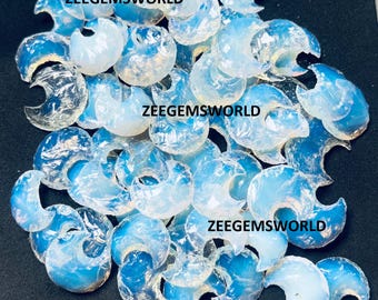 Könnte beinhalten: Eine Sammlung von irisierenden, durchscheinenden, weißen, mondförmigen Opaliten. Die Steine sind auf einem schwarzen Hintergrund zu einem Haufen zusammengelegt. Der Text "Zeegemsworld" erscheint dreimal im Bild.