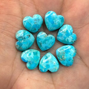 May include: Seven heart-shaped turquoise stones with a bright blue color and natural dark matrix veining. The stones are arranged in a circular pattern, each featuring a smooth, polished surface with distinct variations in color and texture.