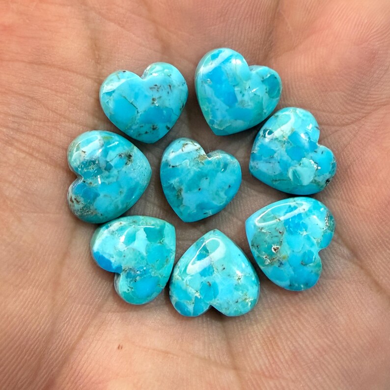 May include: Seven heart-shaped turquoise stones with a bright blue color and natural dark matrix veining. The stones are arranged in a circular pattern, each featuring a smooth, polished surface with distinct variations in color and texture.