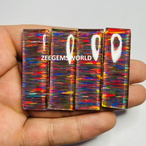 Puede incluir: Cuatro piezas rectangulares de ópalo iridiscente con un arcoíris de colores, incluyendo rojo, naranja, amarillo, verde, azul y morado. El ópalo está engastado en una parte posterior de vidrio o plástico transparente.