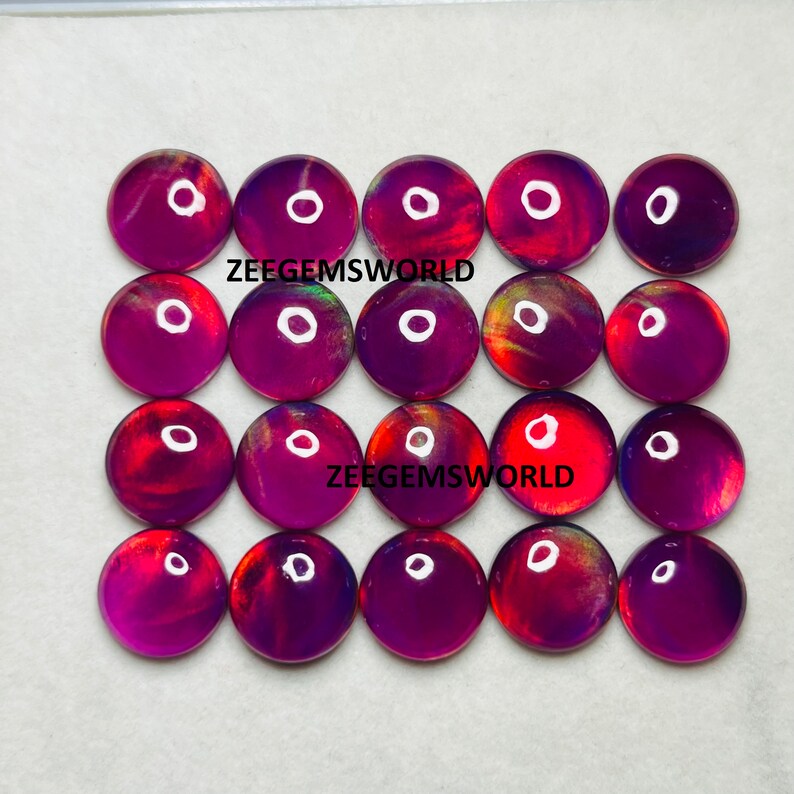 May include: Twenty round, iridescent cabochons in shades of purple, red, and orange. The cabochons are approximately 1 inch in diameter and have a smooth, polished surface.