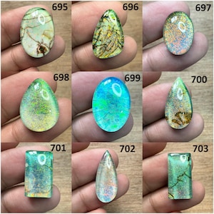 May include: Nine polished gemstones in various shapes, including oval, teardrop, and rectangular. The stones display a range of colors, such as green, blue, and orange, with internal patterns and textures. Each stone is numbered.