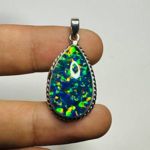 Könnte beinhalten: Ein tropfenförmiger Anhänger mit einer silbernen Fassung und einem grün-blau-orangen Opal-Stein.