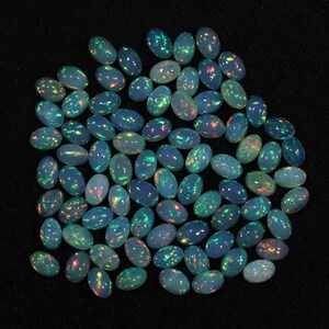 May include: A collection of oval-shaped opal gemstones, with a variety of iridescent colors, including blue, green, and red.