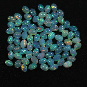 May include: A collection of oval-shaped opal gemstones with iridescent colors, including blue, green, and red.