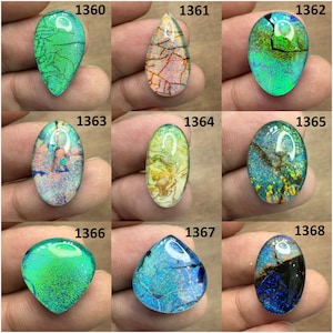 Op de afbeelding: Negen gepolijste opaal edelstenen in verschillende vormen en kleuren. De opalen vertonen een reeks tinten, waaronder groen, blauw, geel en oranje, met interne patronen en scheuren. Elke steen is genummerd van 1360 tot 1368.