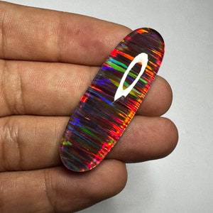 Pu&ograve; includere: Un cabochon di opale iridescente e colorato con un motivo a strisce in tonalit&agrave; di rosso, arancione, verde, blu e viola. L'opale &egrave; di forma ovale e ha una superficie liscia e lucida.