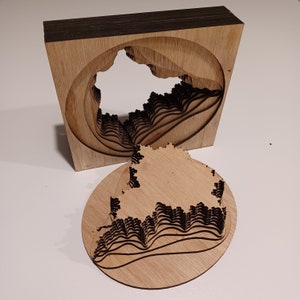 Op de afbeelding: Een 3D-model van hout van een landschap met een gelaagd ontwerp. Het model is gemaakt van meerdere stukken die in elkaar passen om een complex en ingewikkeld ontwerp te creëren. Het model is geverfd in een natuurlijke houtkleur.