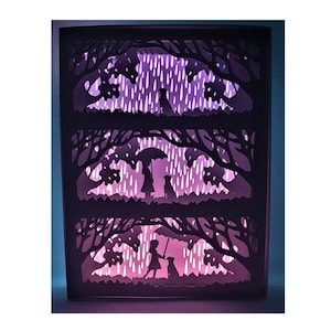 May include: A three-tiered paper cut-out art piece depicting a person walking a dog in the rain under an umbrella. The background is a forest scene with trees and rain. The art piece is illuminated with a purple and pink gradient.