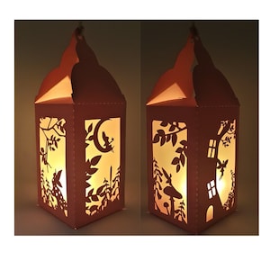 May include: A paper lantern with a fairy and moon design, illuminated from within. The lantern is made of brown paper and has a delicate, intricate design.