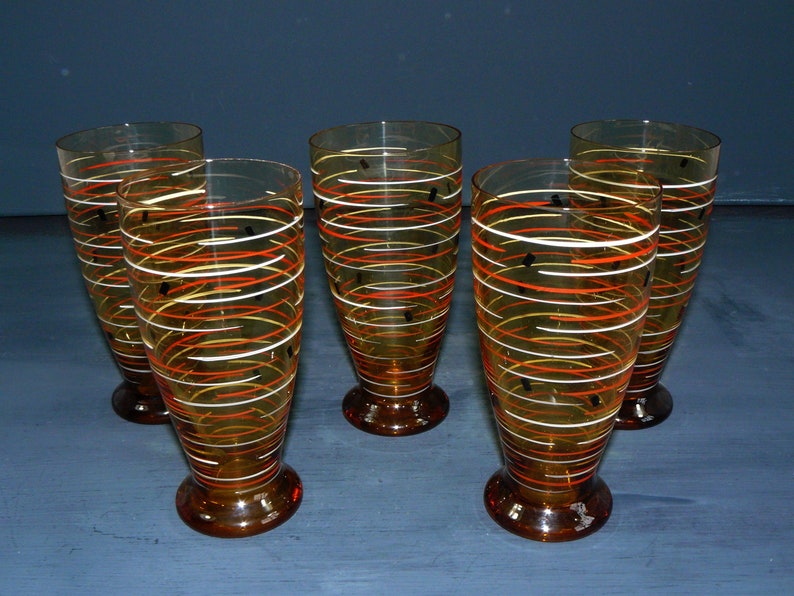 K&ouml;nnte beinhalten: Satz von sechs Trinkgl&auml;sern aus Bernstein-Glas mit einem wirbelnden orange-wei&szlig;en Design und schwarzen Akzenten.