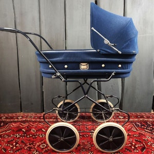 May include: A vintage blue baby stroller with a black metal frame and four wheels. The stroller has a white basket underneath and a blue fabric canopy.