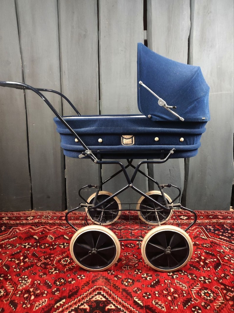 May include: A vintage blue baby stroller with a black metal frame and four wheels. The stroller has a white basket underneath and a blue fabric canopy.