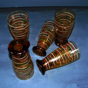 K&ouml;nnte beinhalten: Satz von vier Trinkgl&auml;sern aus Bernstein-Glas mit einem wei&szlig;en und orangefarbenen Streifenmuster.