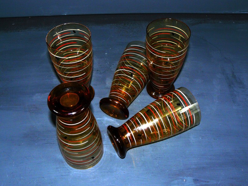 K&ouml;nnte beinhalten: Satz von vier Trinkgl&auml;sern aus Bernstein-Glas mit einem wei&szlig;en und orangefarbenen Streifenmuster.