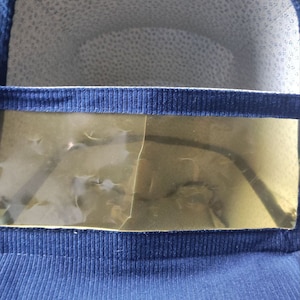 May include: A blue fabric baby carrier with a clear plastic window. The window is slightly cracked.