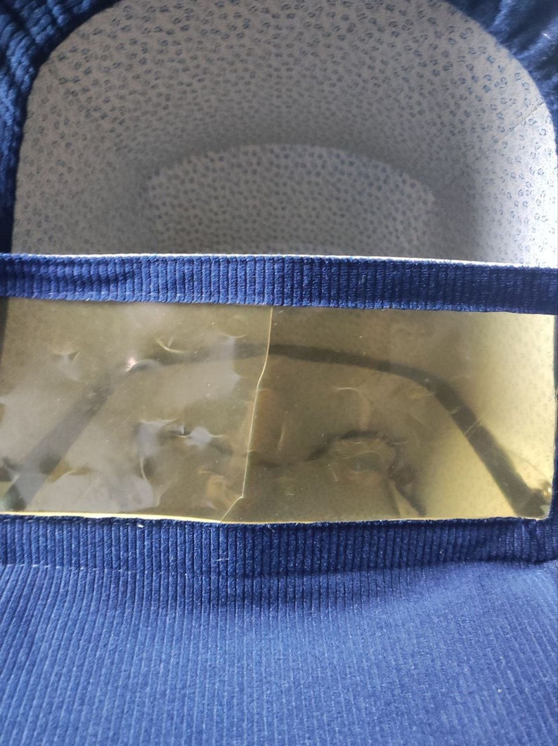 May include: A blue fabric baby carrier with a clear plastic window. The window is slightly cracked.