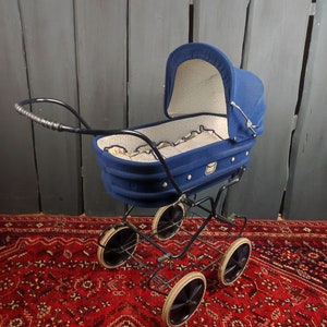 May include: A vintage blue baby stroller with a white and blue patterned lining. The stroller has a black metal frame and four black wheels.