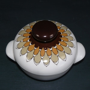 Pode incluir: Prato de cerâmica branca para assar com um design floral marrom e bege. A tampa tem uma pega marrom.