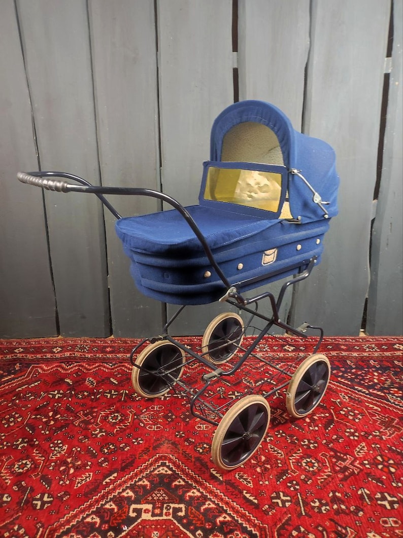 May include: A vintage blue baby stroller with a black metal frame and four wheels. The stroller has a fabric canopy and a basket underneath.
