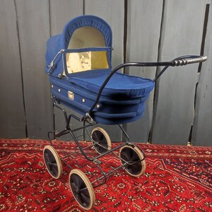May include: A vintage blue baby stroller with a black metal frame and four wheels. The stroller has a fabric canopy and a basket underneath.