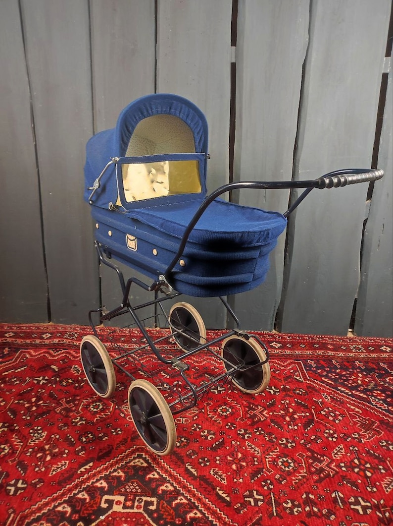 May include: A vintage blue baby stroller with a black metal frame and four wheels. The stroller has a fabric canopy and a basket underneath.