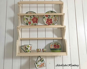 May include: A wooden wall-mounted shelf with four tiers for displaying dishes. The shelf has a curved design and is made of natural wood. It is decorated with colorful ceramic plates and mugs with floral patterns.