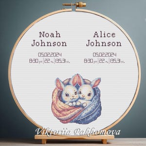 Könnte beinhalten: Kreuzstich-Stickerei in einem Holzreifen. Das Design zeigt zwei kuschelnde Hasen, mit den Namen "Noah Johnson" und "Alice Johnson" darüber. Enthält Geburtsdetails: Datum, Uhrzeit, Länge (55,88 cm) und Gewicht (3835,7 g).