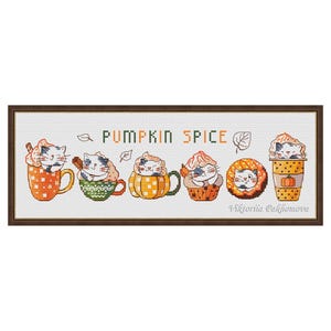 May include: Cross-stitch art showing six cats in pumpkin spice-themed cups and treats. The artwork includes the text "PUMPKIN SPICE" and is framed in a brown wooden frame. The cats are in various poses, adding a touch of whimsy and autumnal charm.
