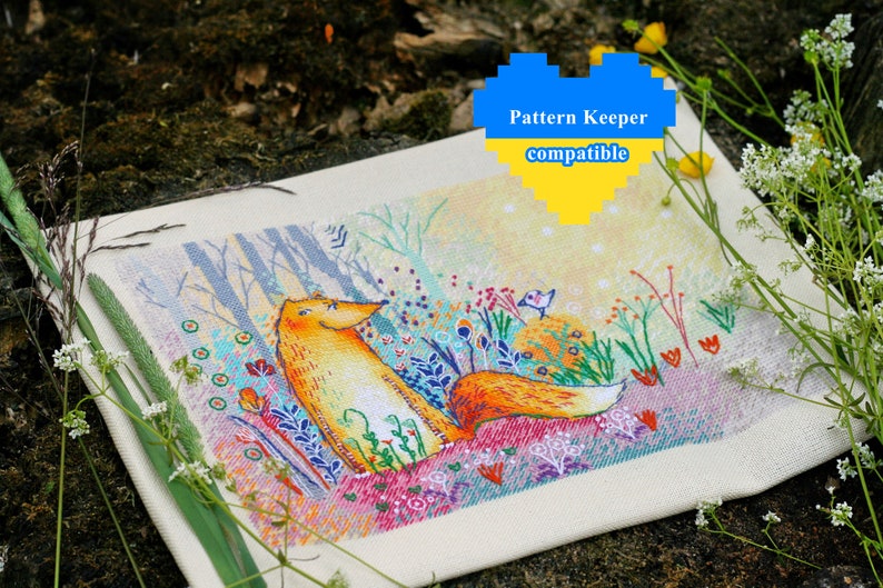Op de afbeelding: Een kruissteekpatroon van een vos die in een veld met bloemen zit. De vos is oranje en wit, en de bloemen zijn in verschillende kleuren. De achtergrond is een lichtblauwe lucht met witte wolken. De tekst "Pattern Keeper compatible" staat in een hartvorm bovenaan de afbeelding.