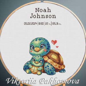 May include: A circular wooden embroidery hoop containing white fabric with a cross-stitch design of two green turtles, two red hearts, and the text Noah Johnson, 05.02.2024, 8:30, 22 in., 135.31 oz., and Viktoriia Pakhomova.