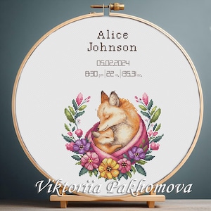 Może przedstawiać: Haft krzyżykowy przedstawiający matkę lisa i małego liska, otoczone kwiatowym wieńcem. Tekst "Alice Johnson" i dane urodzenia są wyświetlane nad ilustracją lisa. Tamborek ma średnicę 55.88 cm.