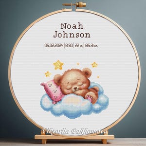 Op de afbeelding: Kruissteekborduurwerk in een houten hoepel met een slapende teddybeer op een wolk met sterren. De tekst luidt "Noah Johnson" en geboortegegevens: 55,88 cm, 3830,5 g.