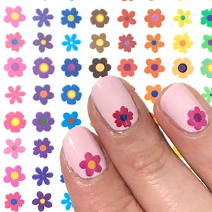 May include: A sheet of colourful flower stickers with a variety of colours and designs. The stickers are shown on a person's fingernails.