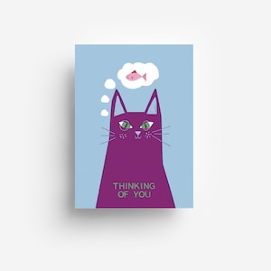 Könnte beinhalten: Eine rechteckige Grußkarte mit hellblauem Hintergrund zeigt eine violette Katze mit grünen Augen. Über der Katze befindet sich eine weiße Gedankenblase mit einem rosa Fisch. Der Text "THINKING OF YOU" ist grün auf der Brust der Katze gedruckt.
