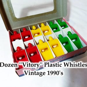 May include: A box of 12 plastic whistles in red, yellow, and green. The box says "Dozen "Vitory" Plastic Whistles Vintage 1990's".