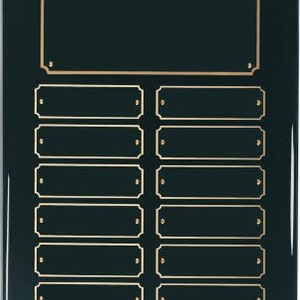 Puede incluir: Una placa verde oscuro con un borde dorado y 13 espacios rectangulares con borde dorado para grabar nombres. El espacio superior es más grande que los demás.