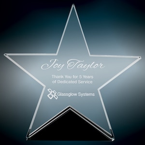 Puede incluir: Un premio en forma de estrella de cristal transparente con una base negra. La estrella tiene el texto "Joy Taylor" y "Thank You for 5 Years of Dedicated Service" grabado. La base tiene el logotipo "Glassglow Systems" grabado.