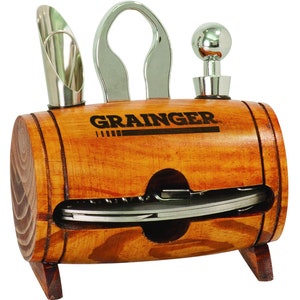May include: A wooden barrel-shaped holder with a silver bottle opener, a silver cork screw, a silver bottle stopper, and a silver pourer. The barrel is engraved with the word "GRAINGER".