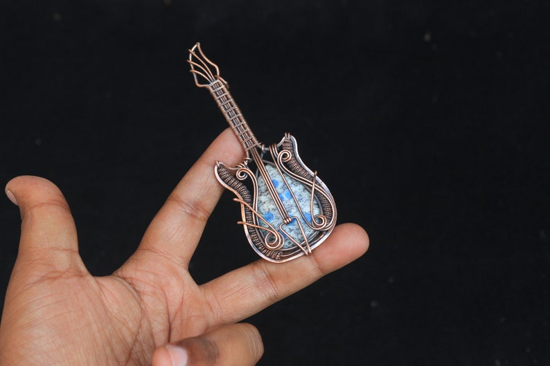 May include: A copper wire wrapped guitar pendant with a blue and white stone inlay.