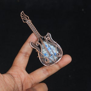 May include: A copper wire wrapped guitar pendant with a blue and white stone inlay.