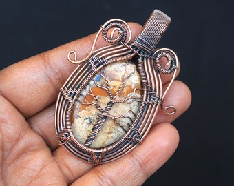 May include: A copper wire wrapped pendant featuring a tree-like pattern in a brown and white agate stone.